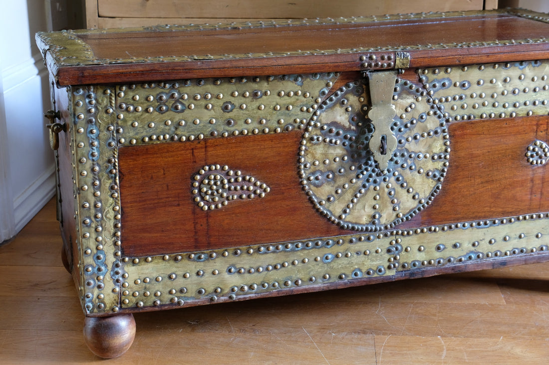 Teak Zanzibar chest decorated with brass studs raised on bun feet
