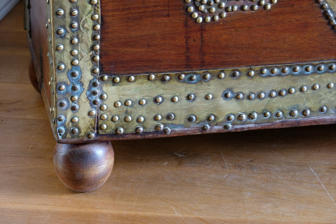 Teak Zanzibar chest decorated with brass studs raised on bun feet