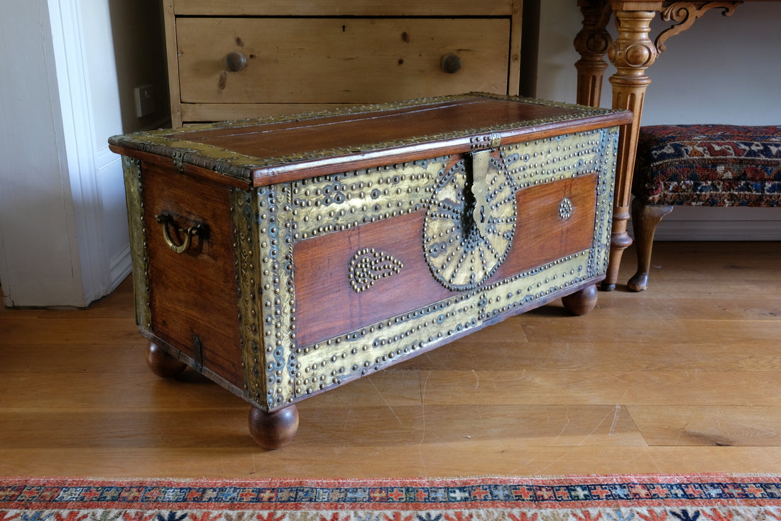 Teak Zanzibar chest decorated with brass studs raised on bun feet