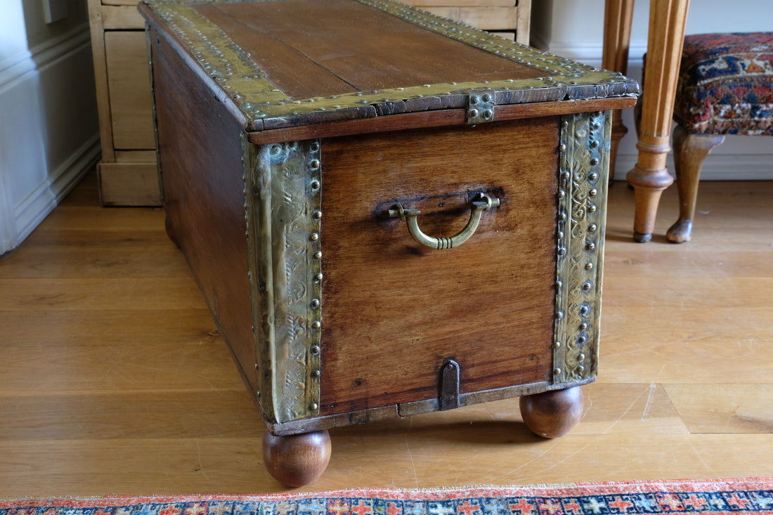 Teak Zanzibar chest decorated with brass studs raised on bun feet