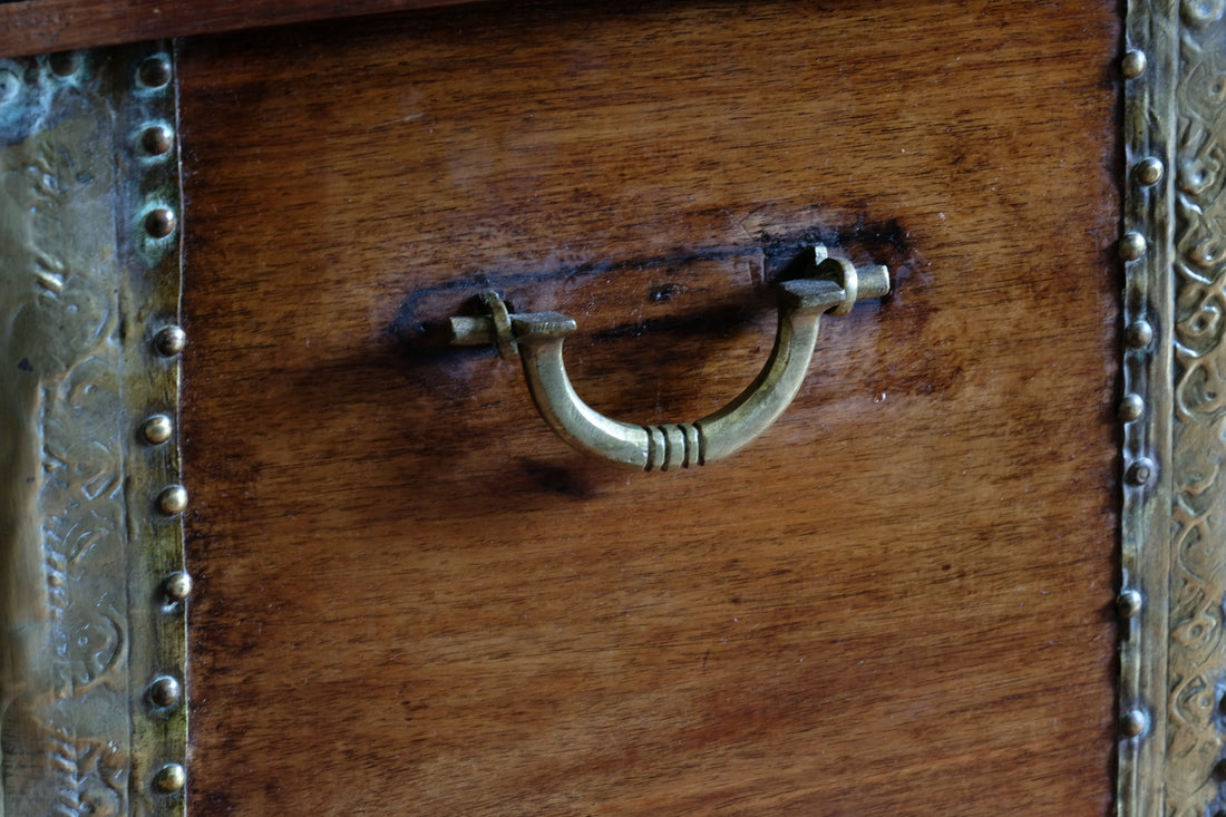 Teak Zanzibar chest decorated with brass studs raised on bun feet
