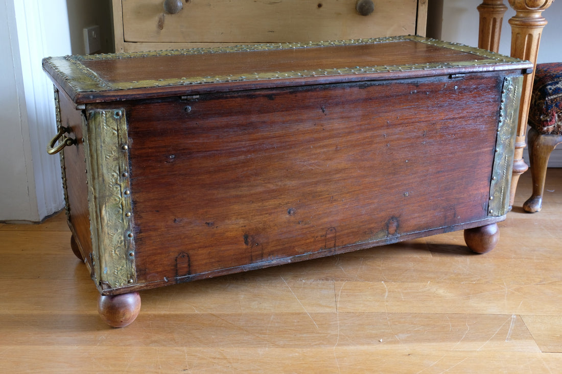 Teak Zanzibar chest decorated with brass studs raised on bun feet