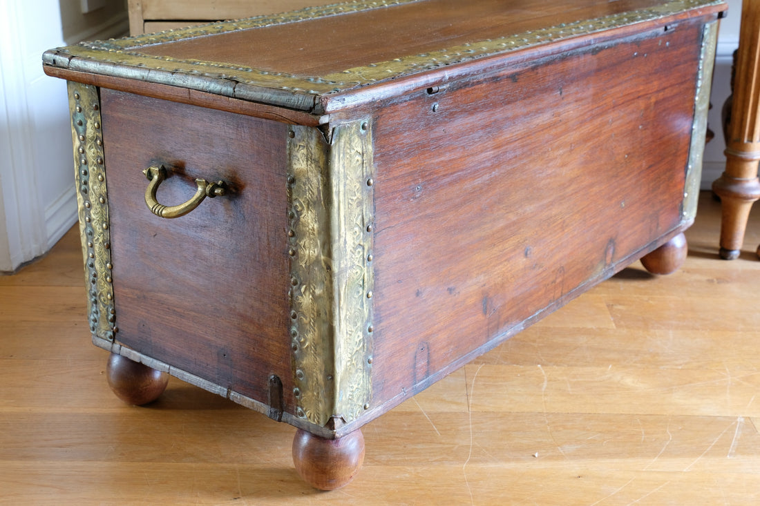 Teak Zanzibar chest decorated with brass studs raised on bun feet