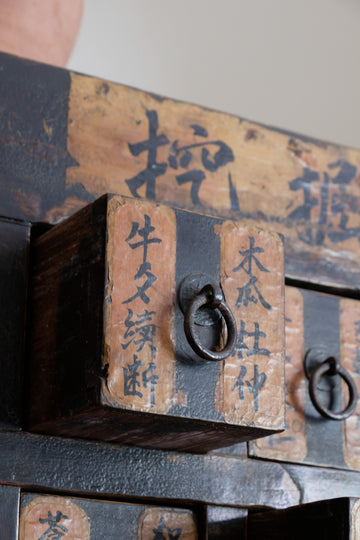 Close-up of antique Chinese storage drawers with hand-painted calligraphy