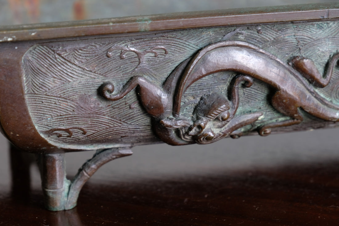 Close-up of dragon and cloud relief on Meiji Japanese bronze suiban vessel