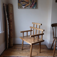 Primitive handmade wooden armchair with rustic timber finish and blocky carved design