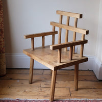 Primitive handmade wooden armchair with rustic timber finish and blocky carved design