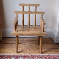 front view - primitive handmade wooden armchair with rustic timber finish and blocky carved design