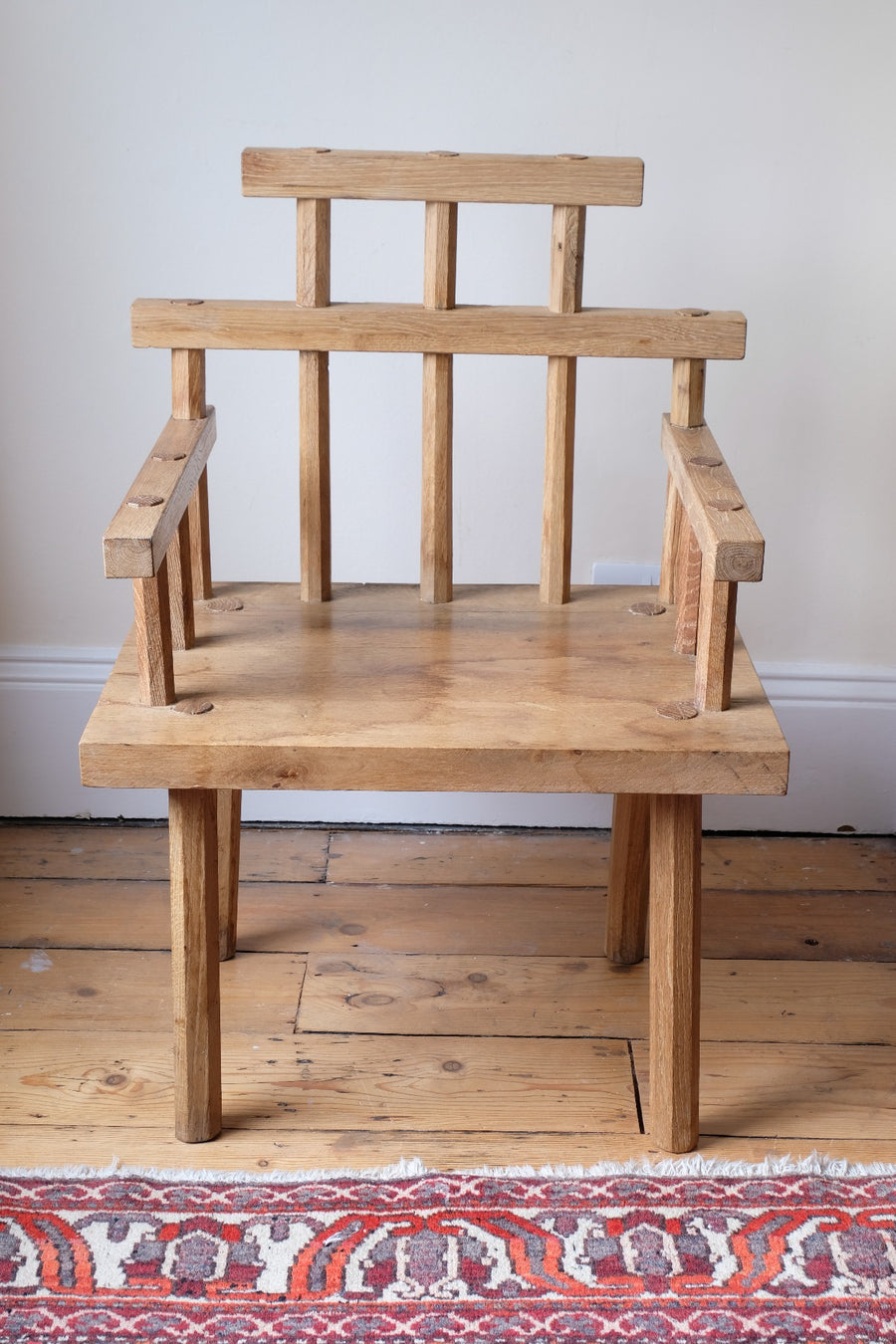 front view - Primitive handmade wooden armchair with rustic timber finish and blocky carved design