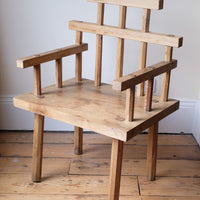 Primitive handmade wooden armchair with rustic timber finish and blocky carved design