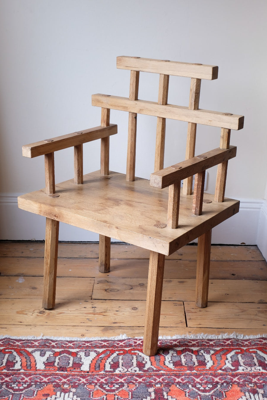 Primitive handmade wooden armchair with rustic timber finish and blocky carved design