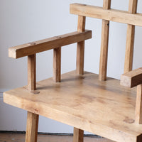 Close up - Primitive handmade wooden armchair with rustic timber finish and blocky carved design