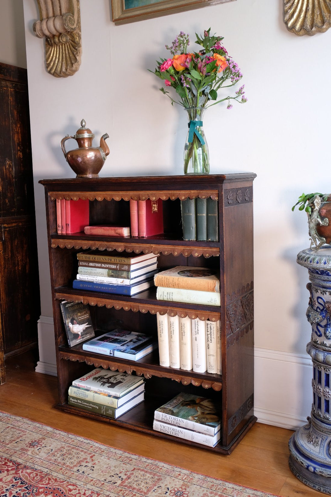Side view detail of carved arts & crafts end panels  - Edwardian Arts and Crafts carved oak bookcase with original tooled leather dust fringing shelves