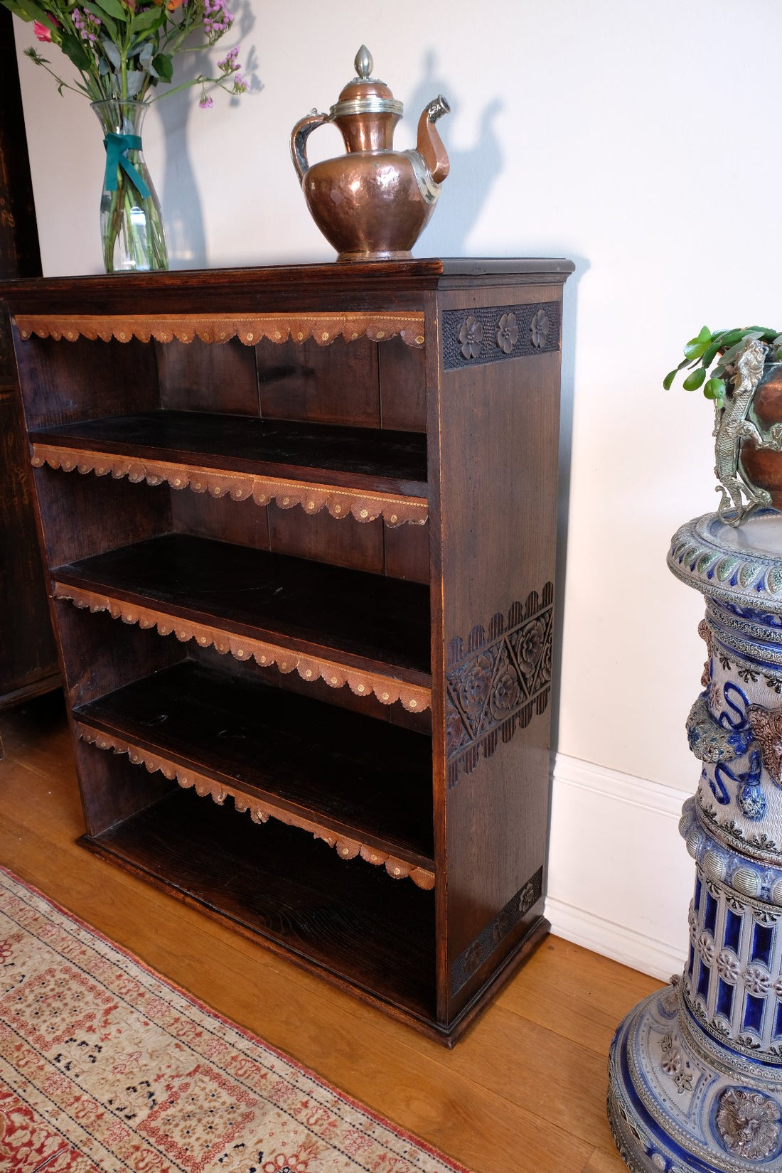 Side view detail of carved arts & crafts end panels  - Edwardian Arts and Crafts carved oak bookcase with original tooled leather dust fringing shelves