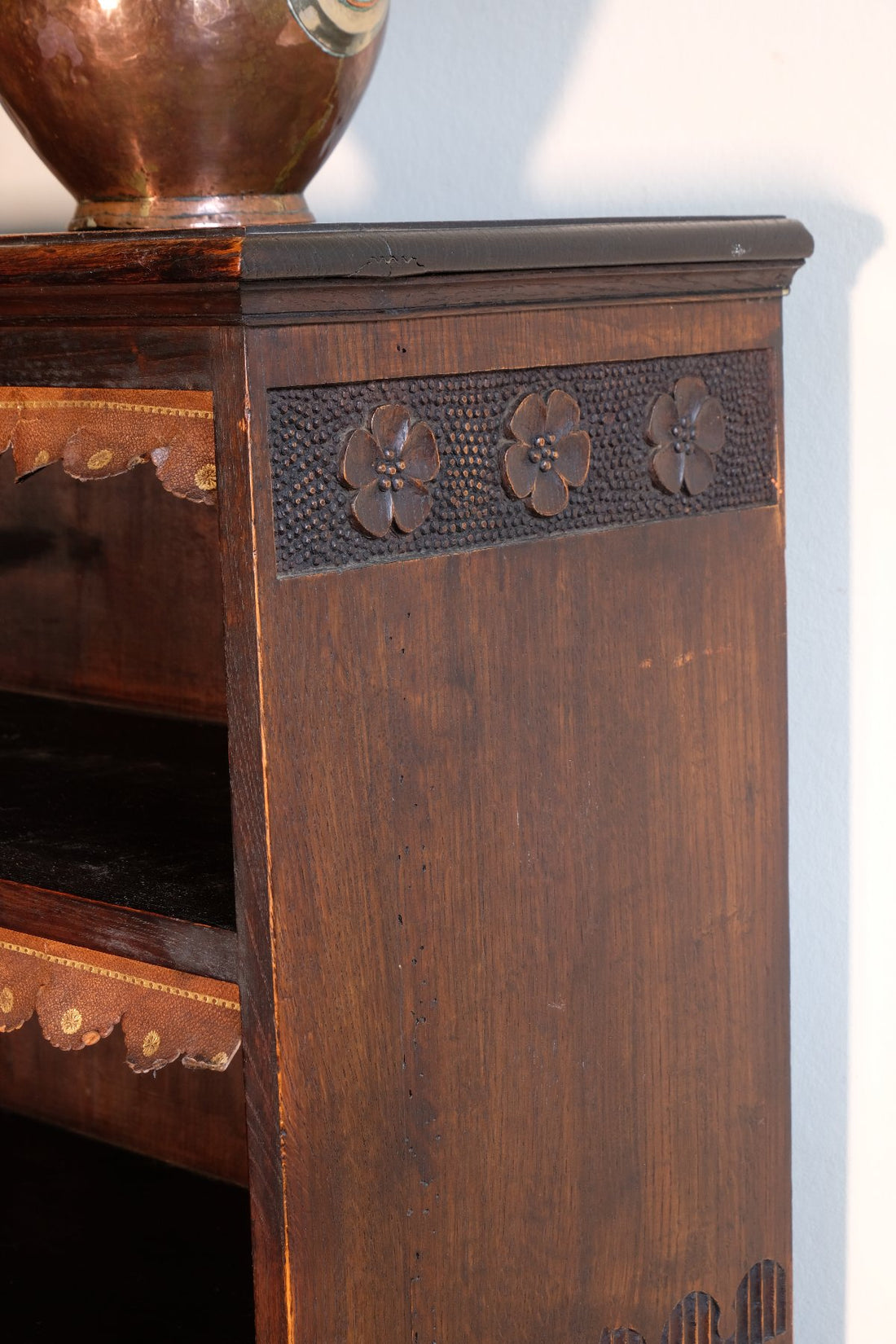chip carved view of a Edwardian Arts and Crafts carved oak bookcase with original tooled leather dust fringing shelves