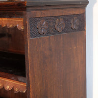 chip carved view of a Edwardian Arts and Crafts carved oak bookcase with original tooled leather dust fringing shelves