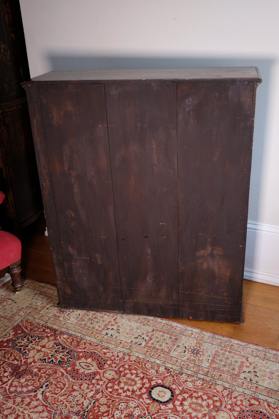 Three panelled back of a Edwardian Arts and Crafts carved oak bookcase with original tooled leather dust fringing shelves