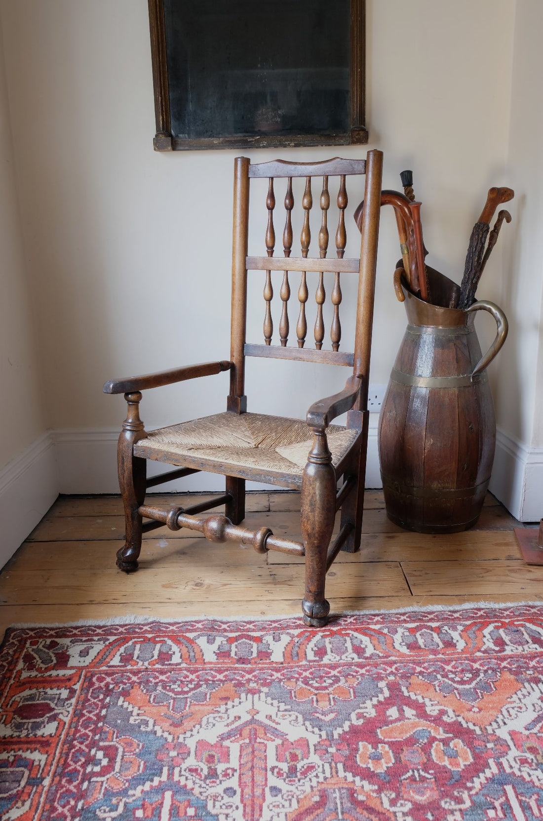 Three quarter view of antique Lancashire oak spindle back armchair with rush seat