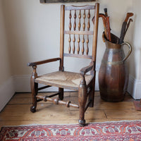 Three quarter view of antique Lancashire oak spindle back armchair with rush seat