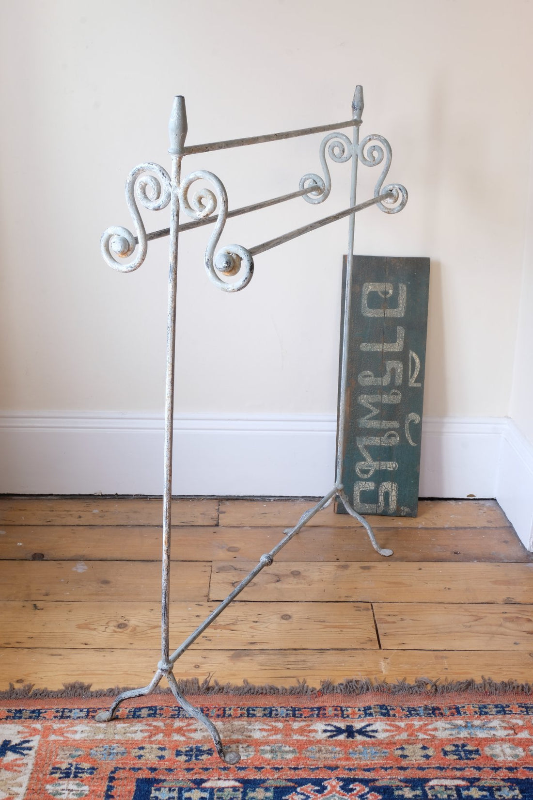 Early 20th century wrought iron freestanding towel rail with scroll ends and aged painted finish