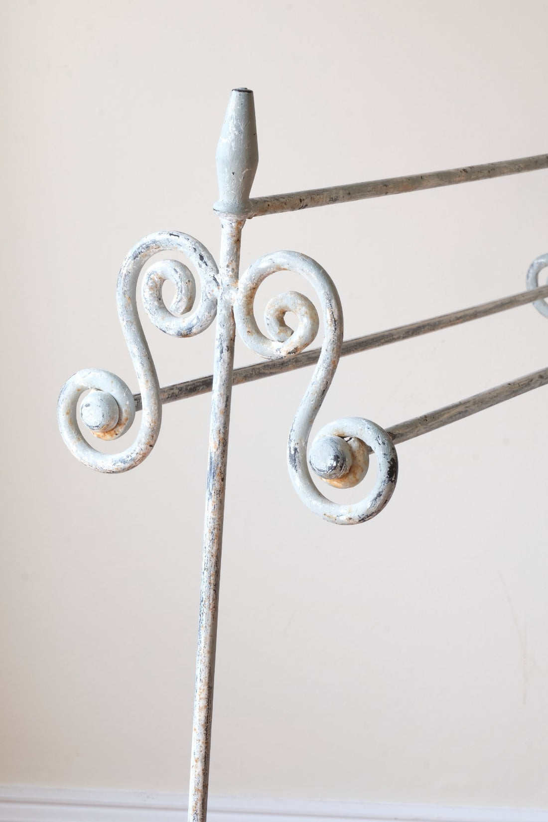 close up of scroll work and finial - Early 20th century wrought iron freestanding towel rail with scroll ends and aged painted finish