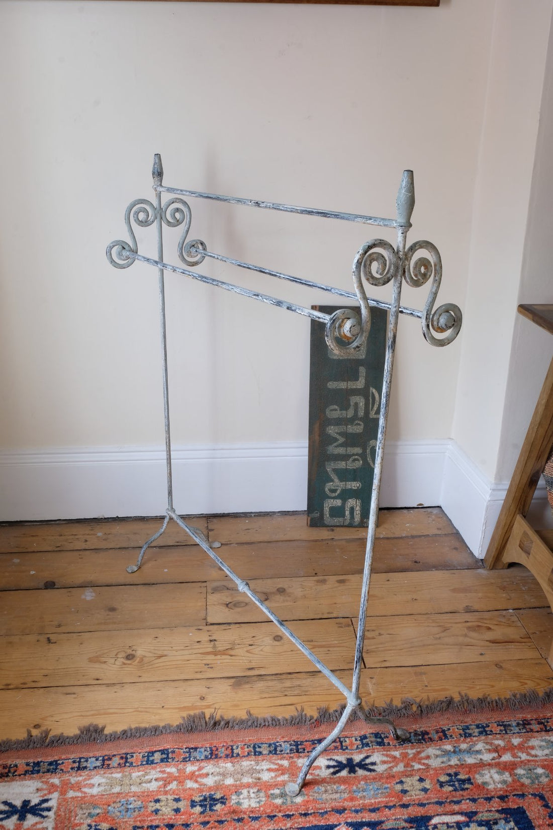 Early 20th century wrought iron freestanding towel rail with scroll ends and aged painted finish
