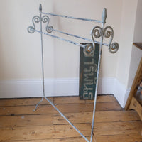 Early 20th century wrought iron freestanding towel rail with scroll ends and aged painted finish