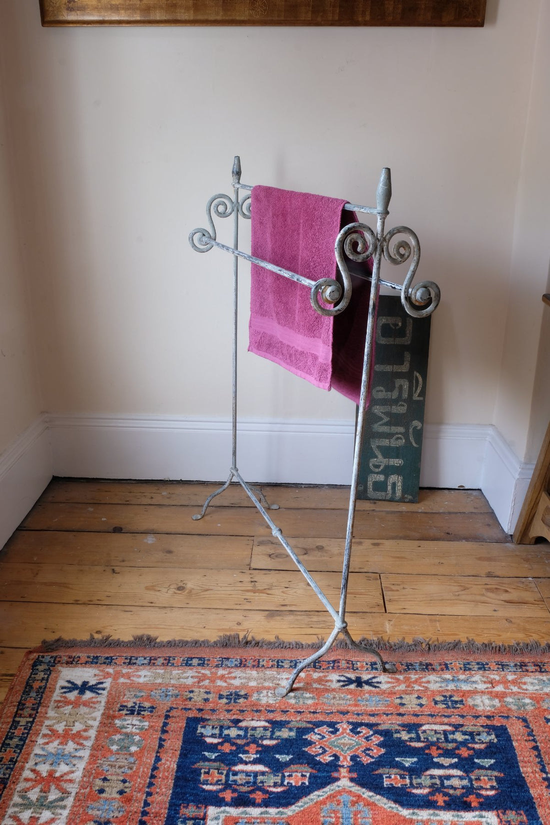 Towel hanging on Early 20th century wrought iron freestanding towel rail with scroll ends and aged painted finish