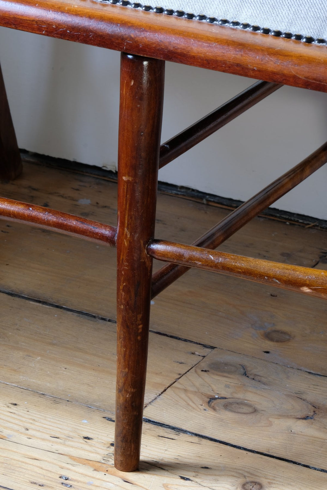 Legs on a 19th century English beech ladder-back bench with linen upholstered horsehair seat and waved slats
