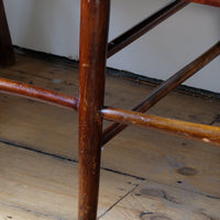 Legs on a 19th century English beech ladder-back bench with linen upholstered horsehair seat and waved slats