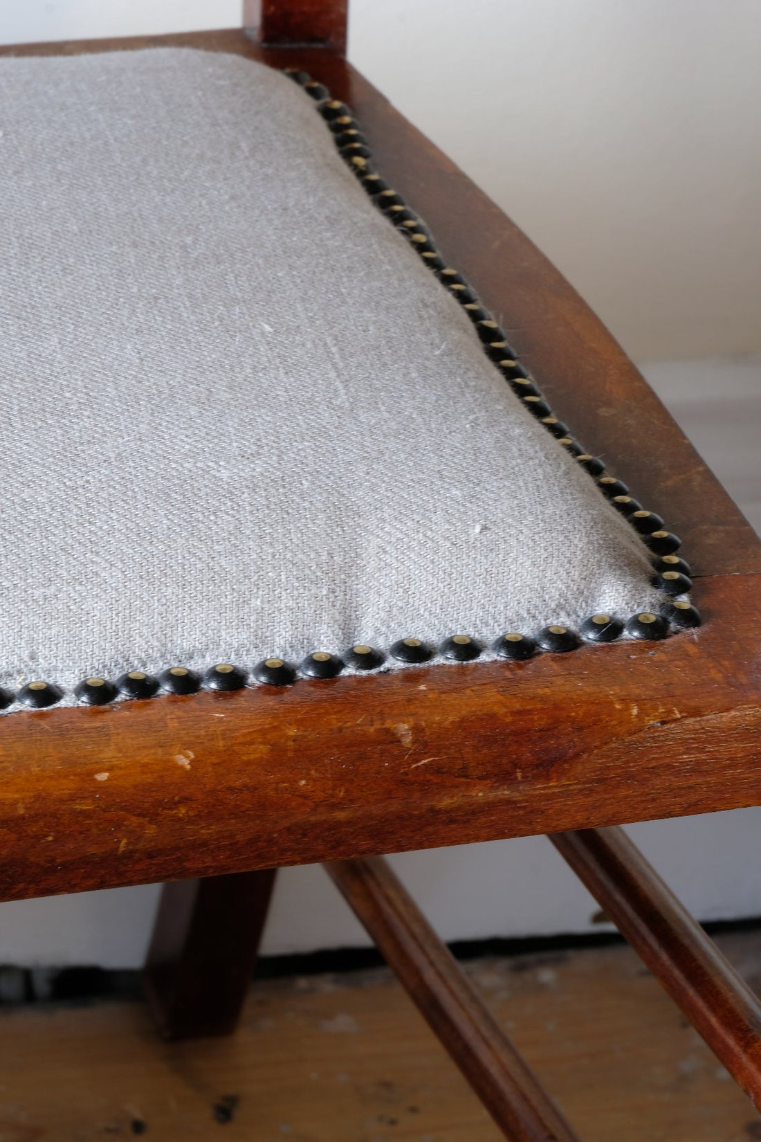 Linen stud work seat on a 19th century English beech ladder-back bench with linen upholstered horsehair seat and waved slats