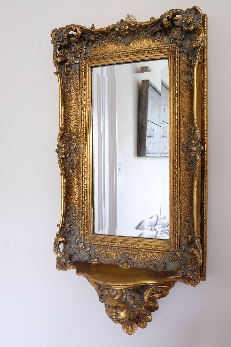 Late Victorian gilt wall mirror with original bevelled mirror plate and cherub shelf detail