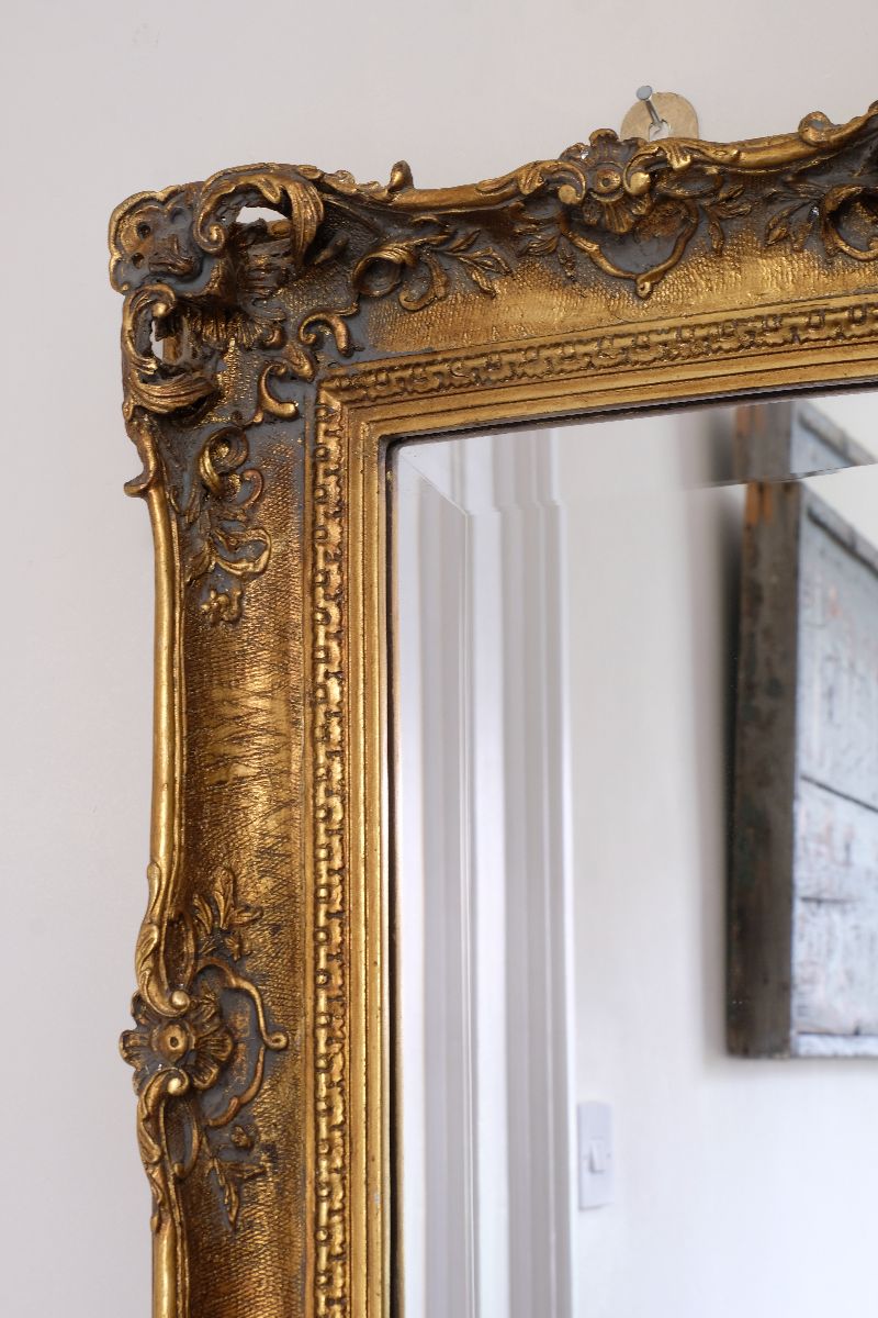 Close up corner view of a Late Victorian gilt wall mirror with original bevelled mirror plate and cherub shelf detail