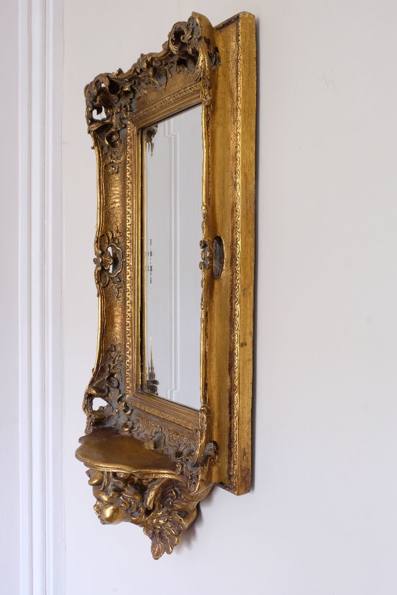 Side profile view of a Late Victorian gilt wall mirror with original bevelled mirror plate and cherub shelf detail
