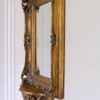 Side profile view of a Late Victorian gilt wall mirror with original bevelled mirror plate and cherub shelf detail