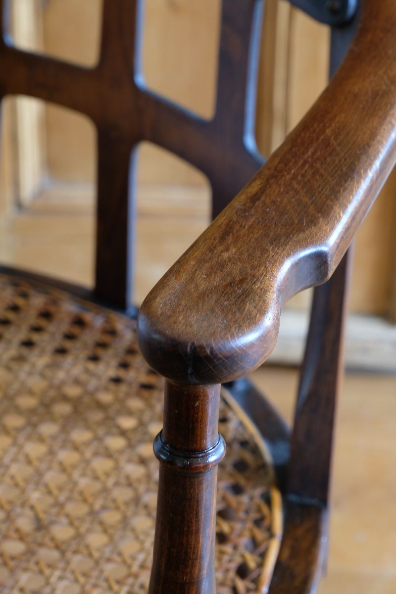 Close up view of the curved notched arms on a Rare Edwardian bentwood lattice back armchair attributed to Jas Shoolbred with pierced Arts & Crafts design 