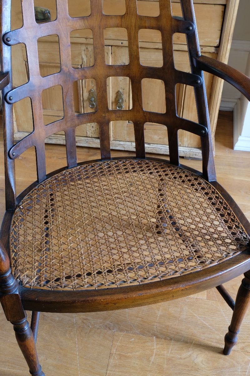 View of the cane seat on a Rare Edwardian bentwood lattice back armchair attributed to Jas Shoolbred with pierced Arts & Crafts design 