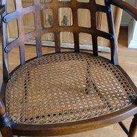View of the cane seat on a Rare Edwardian bentwood lattice back armchair attributed to Jas Shoolbred with pierced Arts & Crafts design 