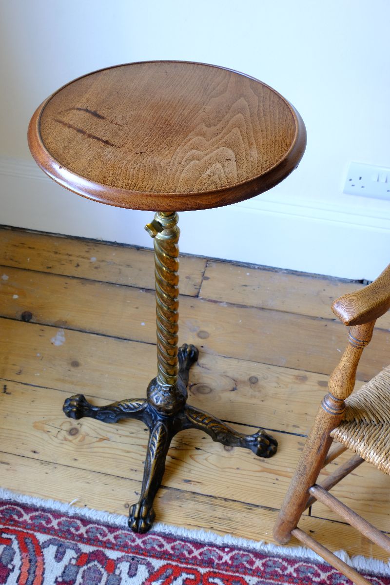 Top down view on an Antique Victorian brass telescopic wine table with mahogany top and lion’s paw feet