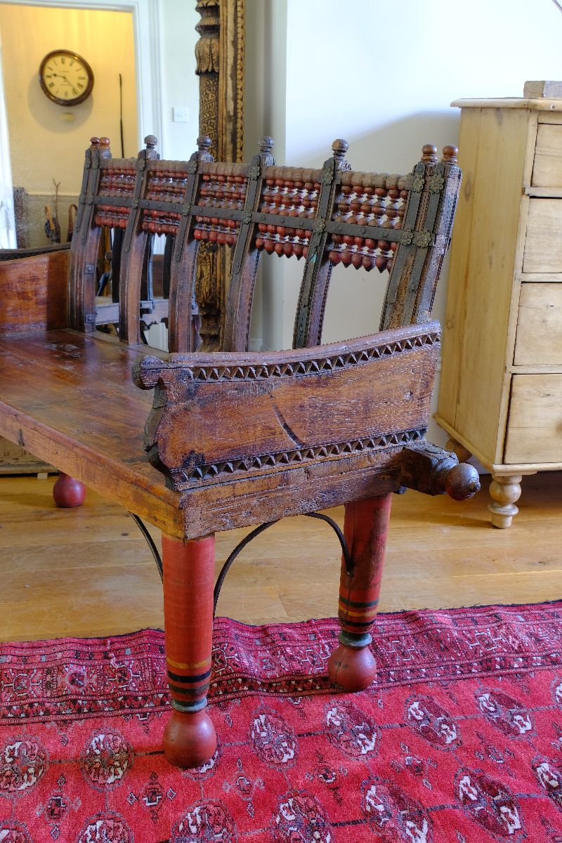 Chipped carved arm support on a Late 19th Century Gujarati Hardwood Hall Bench with Original Polychrome Finish, Turned Gallery Back and Brass Rosette Mounts