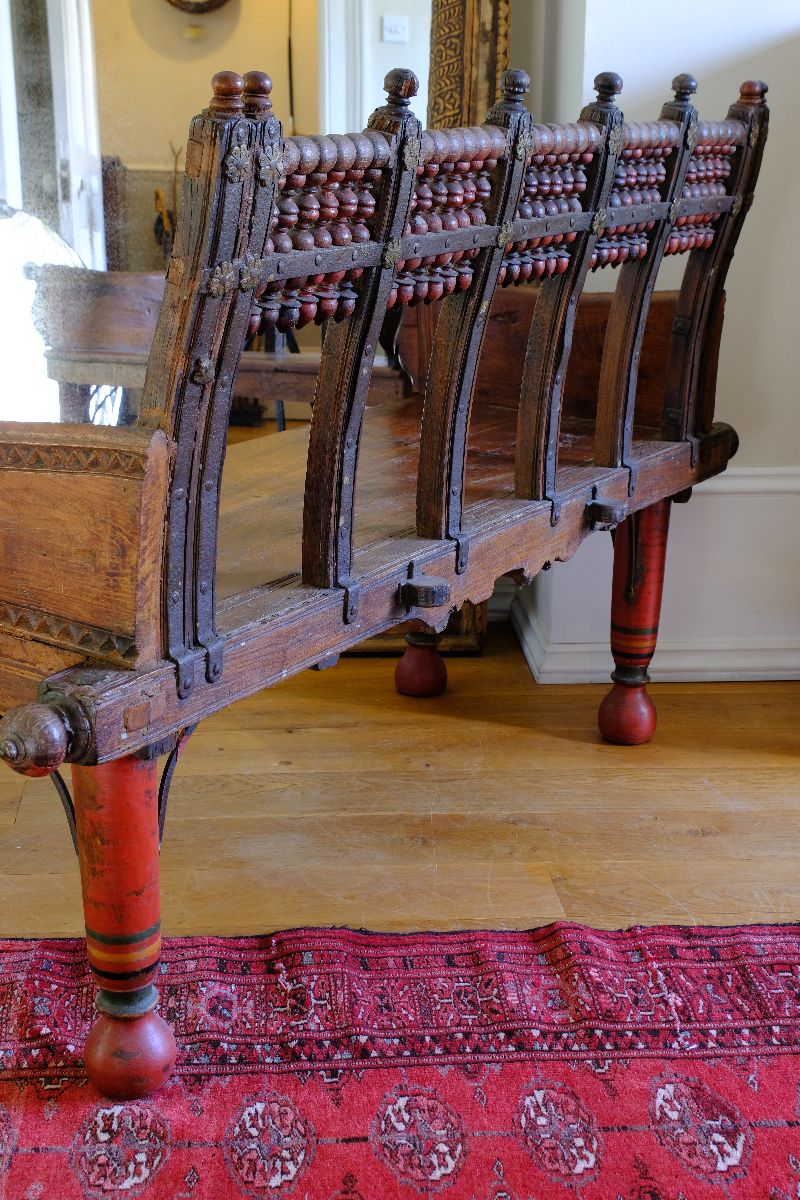 The back is as important as the front on this Late 19th Century Gujarati Hardwood Hall Bench with Original Polychrome Finish, Turned Gallery Back and Brass Rosette Mounts