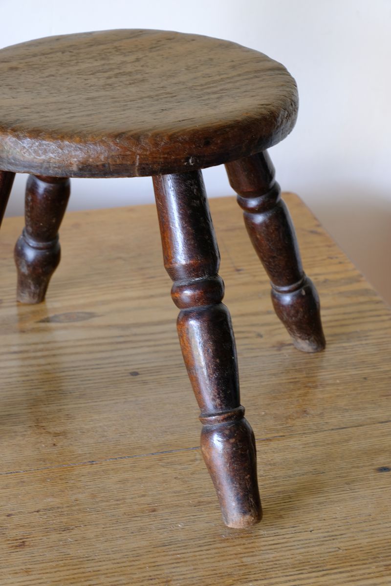 Antique English dairy milking stool with four turned legs and original dark painted finish
