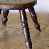 Antique English dairy milking stool with four turned legs and original dark painted finish