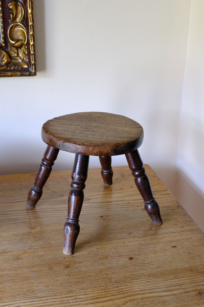 Antique English dairy milking stool with four turned legs and original dark painted finish