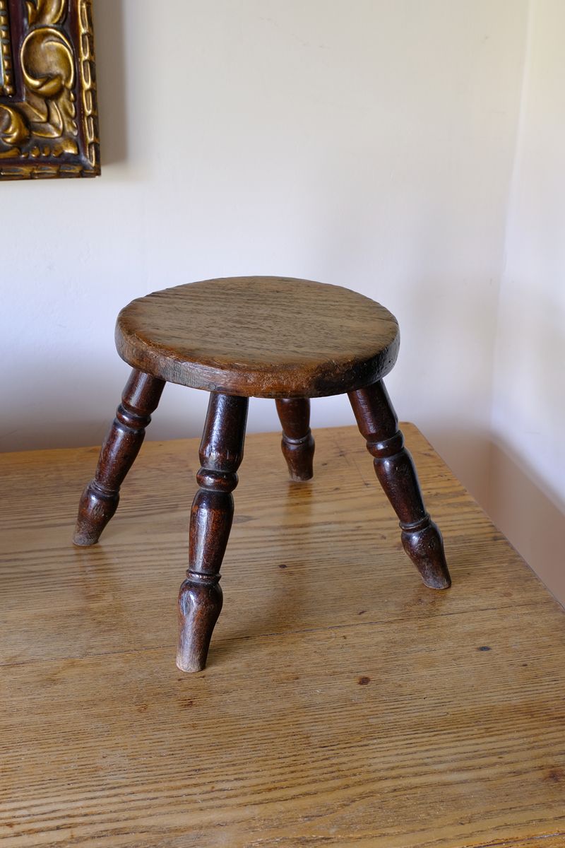 Antique English dairy milking stool with four turned legs and original dark painted finish