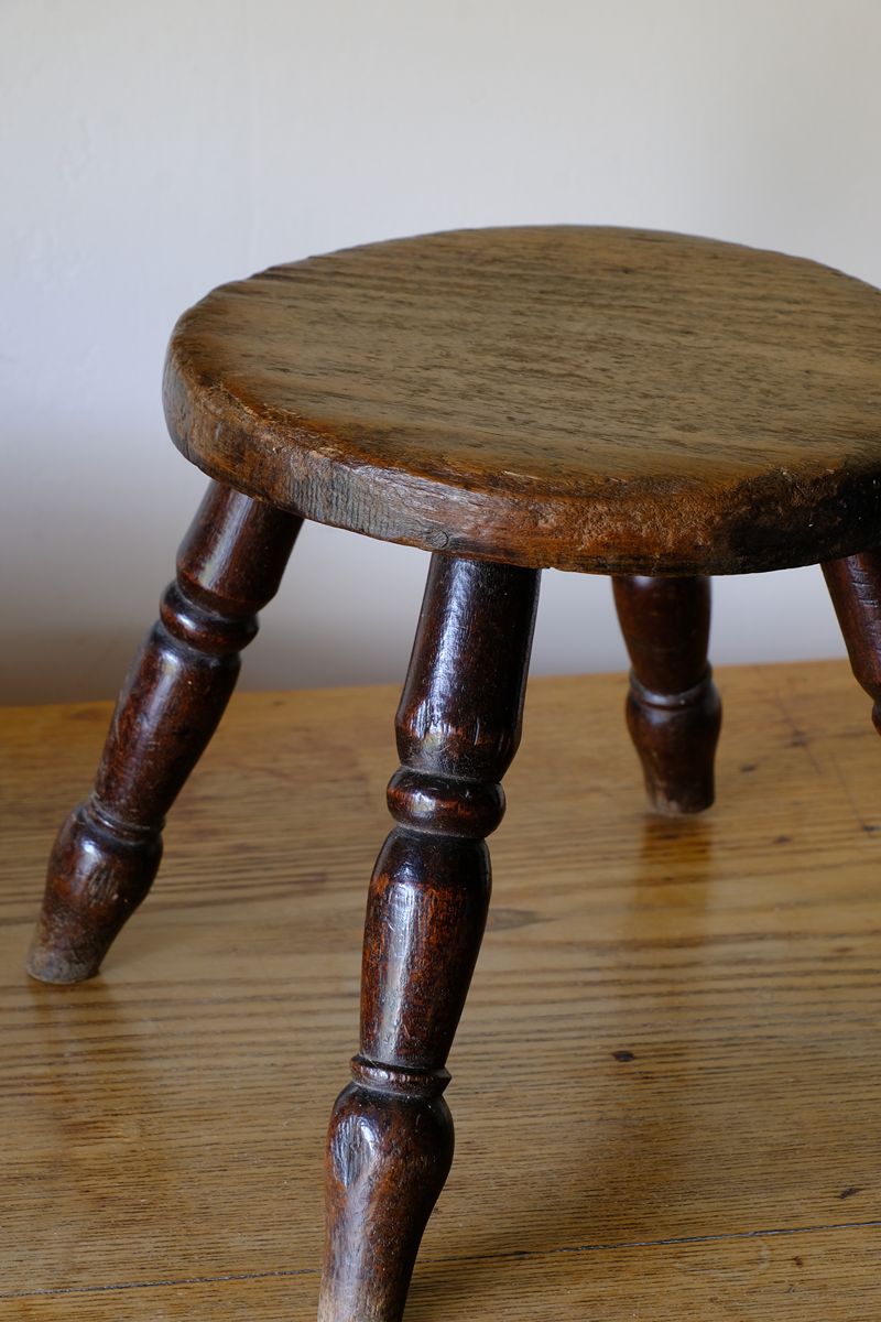 Antique English dairy milking stool with four turned legs and original dark painted finish