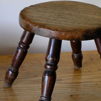 Antique English dairy milking stool with four turned legs and original dark painted finish