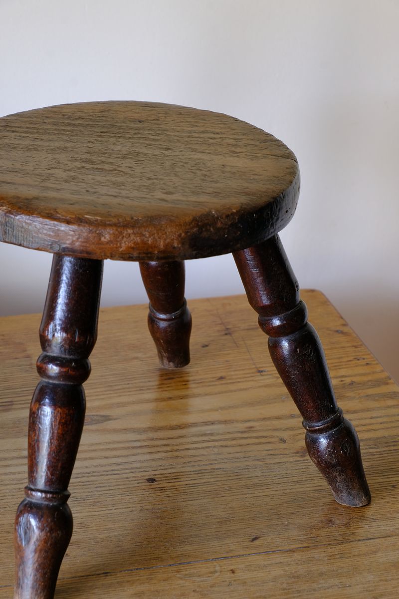 Antique English dairy milking stool with four turned legs and original dark painted finish
