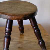 Antique English dairy milking stool with four turned legs and original dark painted finish