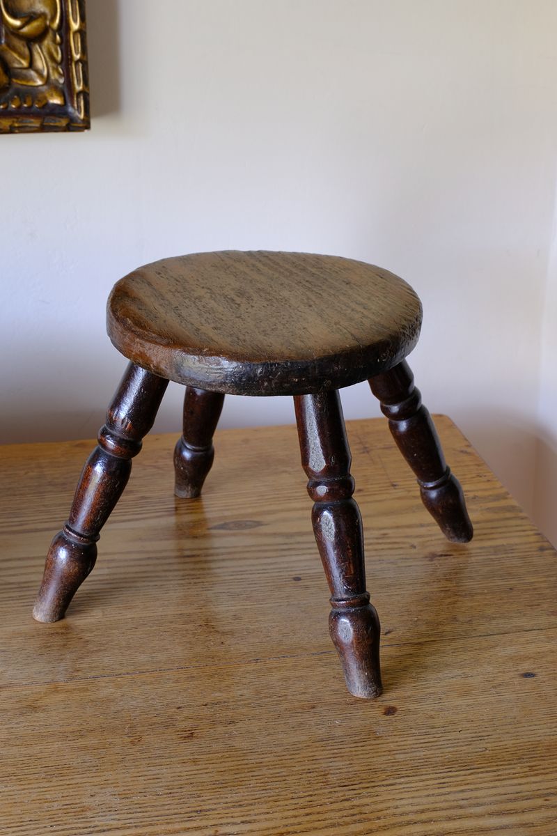 Antique English dairy milking stool with four turned legs and original dark painted finish